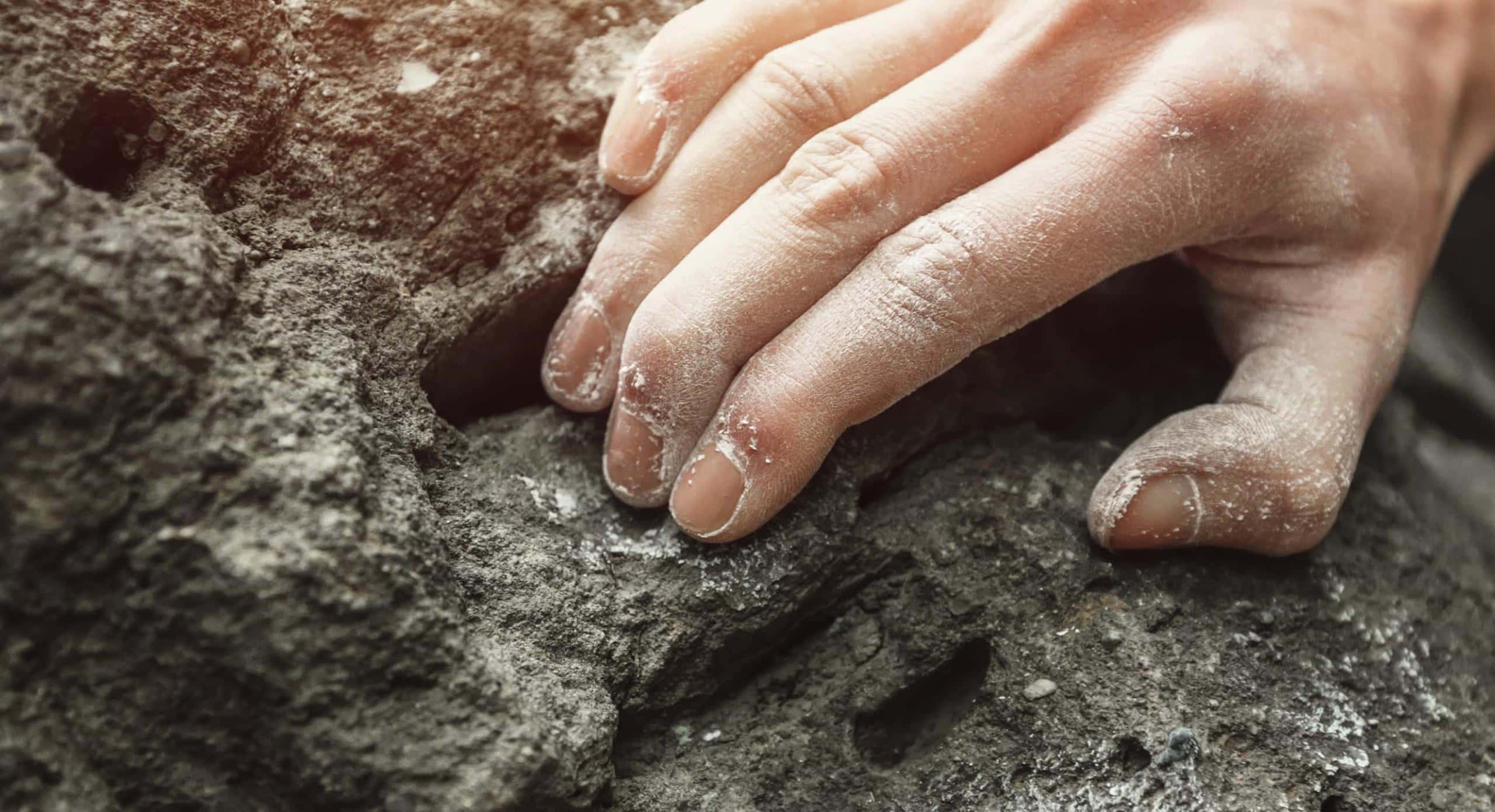 Hand eines Kletterer greift in einen Stein.