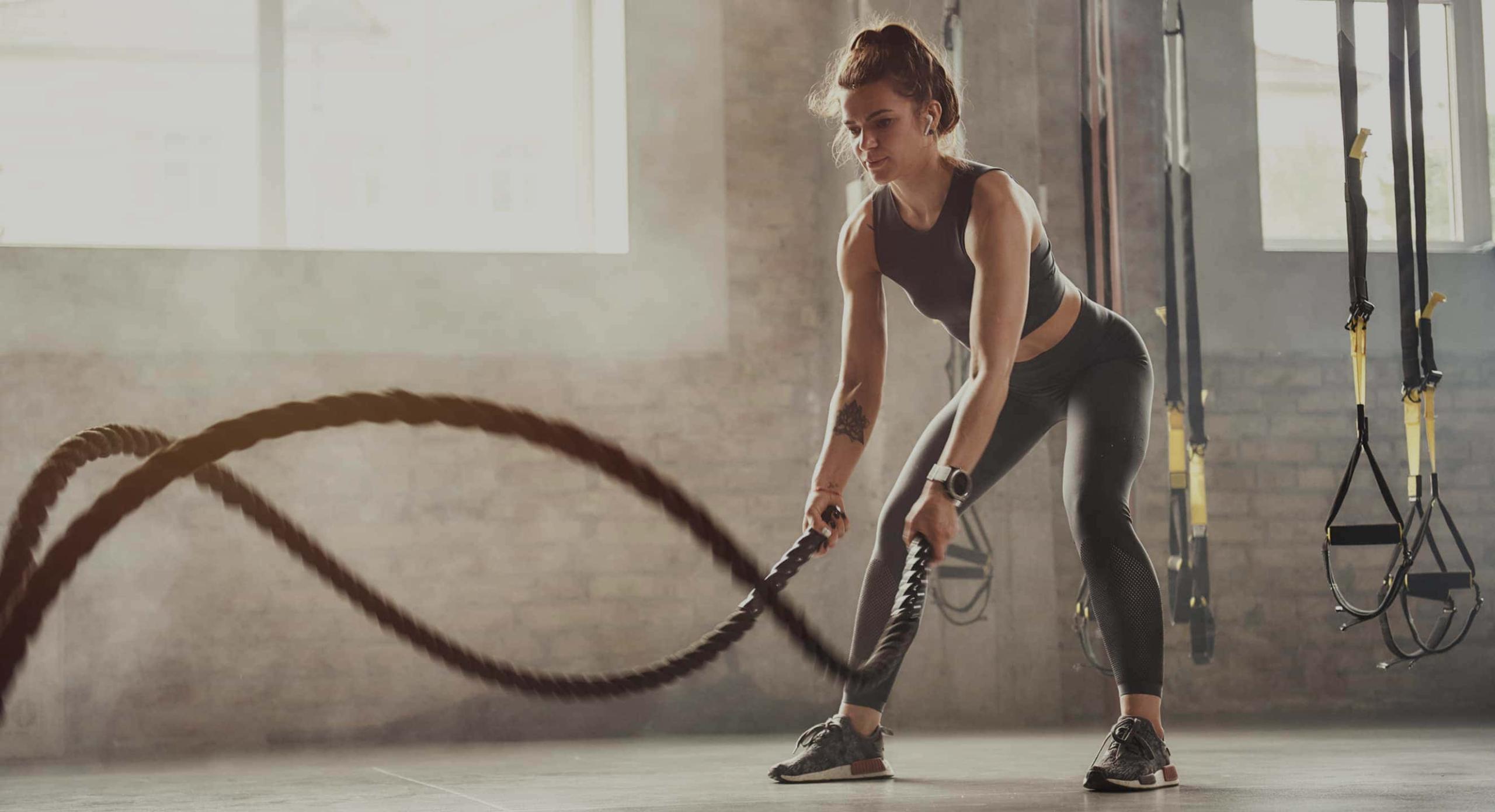 Eine Frau trainiert mit einer Battle Rope in einem Fitnessstudio